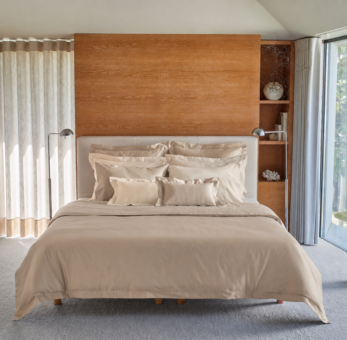 A neatly made bed with a Taupe bedding called the Vincent by BOVI and matching pillows, set against a light wood headboard and built-in shelving in a bright, modern bedroom.