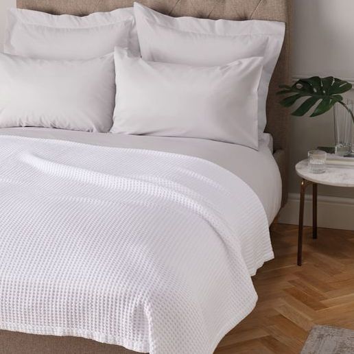 Neatly made bed with white bedding and pillows in a bedroom setting.