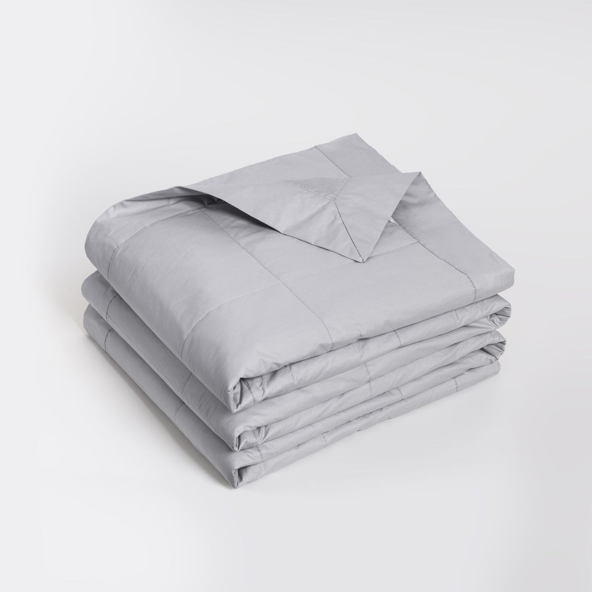 A folded light gray quilted coverlet, neatly stacked on a clean white studio background.