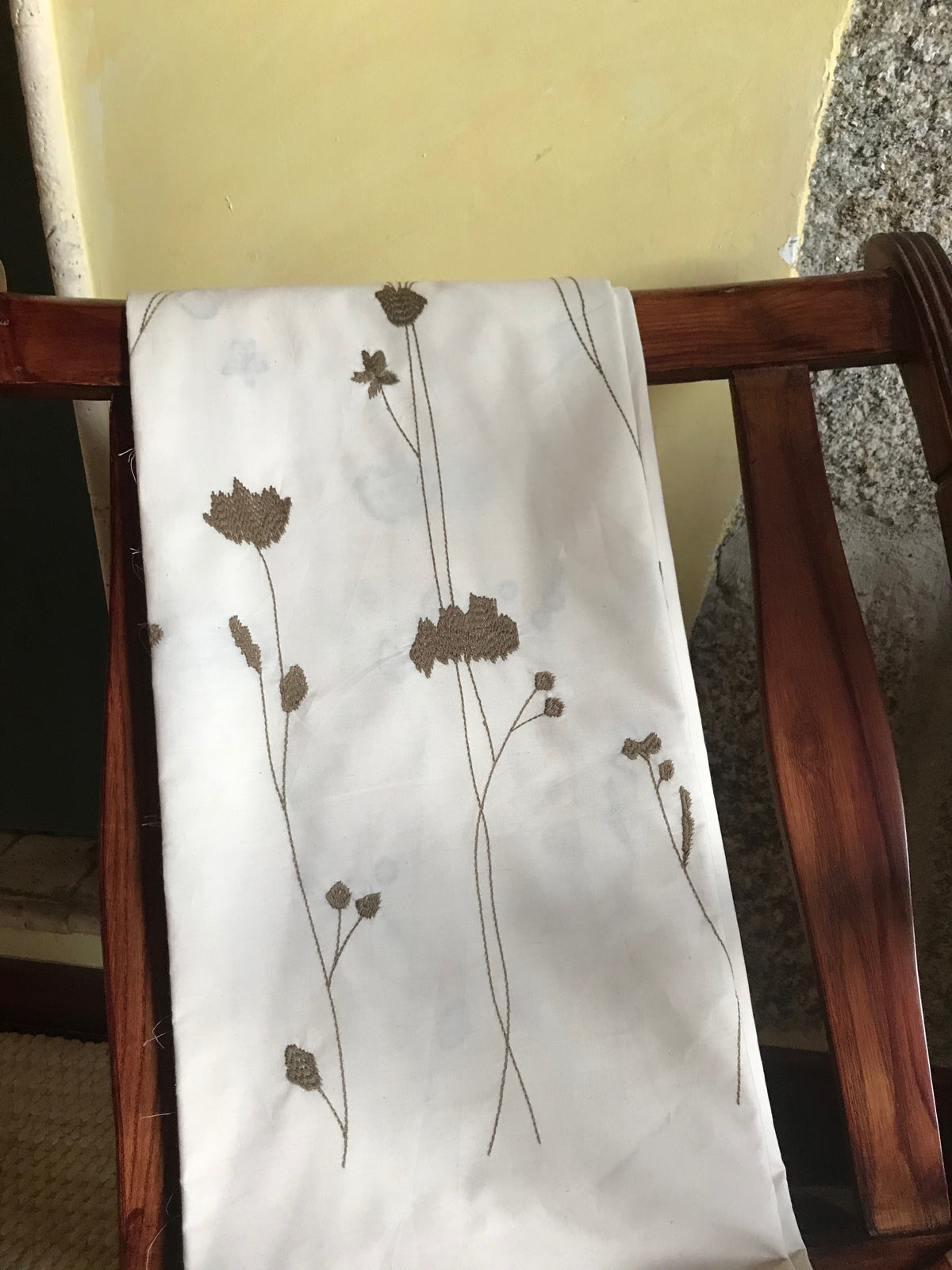 The Amalia Duvet cover by BOVI with olive floral and botanical pattern draped over a dark wooden chair.