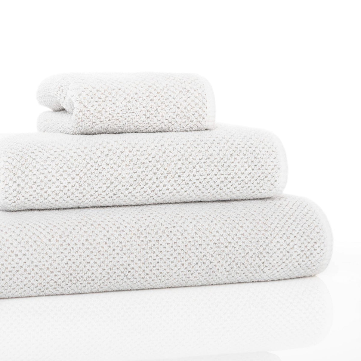 Set of three white towels stacked on a white background