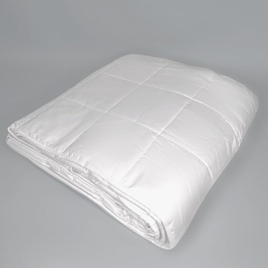 A folded white quilted comforter or duvet with stitched grid sections, photographed on a plain light gray studio background.