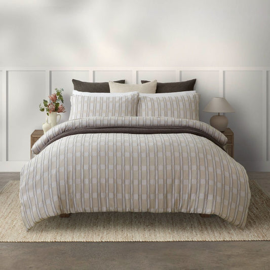 Neatly made bed with Beige & white checkered bedding in a bedroom setting.